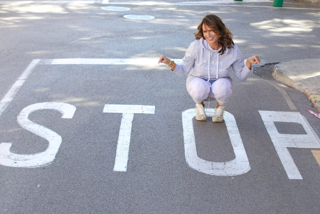 Karin Kuschik hockt auf einer Straße, wo das Wort Stop auf dem Boden geschrieben steht
